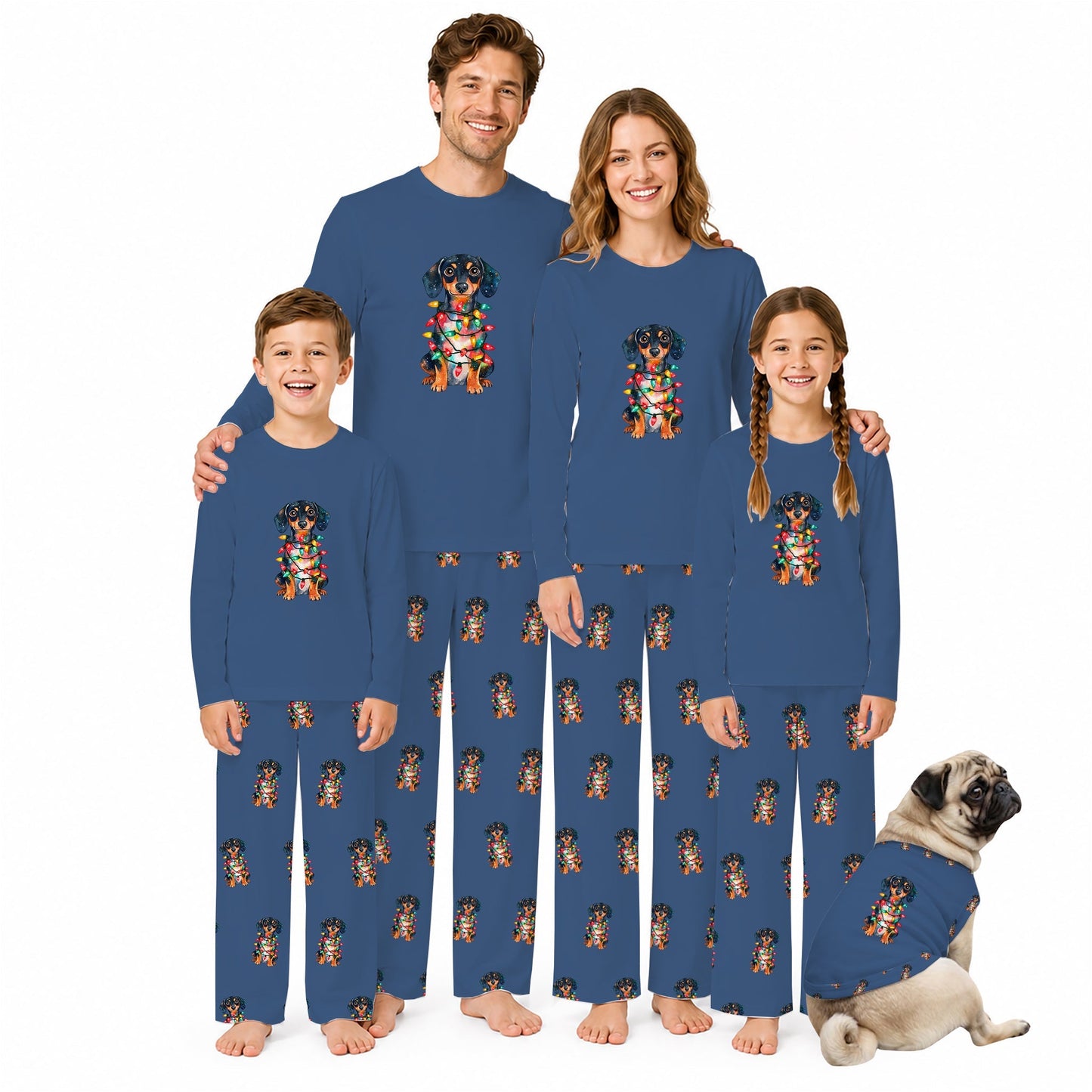 A family of four wearing matching long-sleeve pajamas with a colorful dog graphic on the chest and a repeating dog print on the pants, standing together on a White background with a pug lying at their feet.