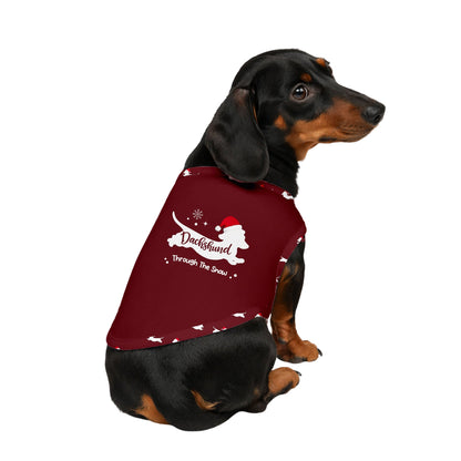 A dachshund wearing a maroon Christmas-themed dog sweater with White text reading 'Dachshund Through The Snow' and a White dog silhouette, shown against a plain White background.