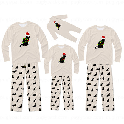 Three sizes of matching family Christmas pajamas shown on a white background, featuring a beige long-sleeve top with a black cat wearing a green Christmas tree and red Santa hat, paired with beige pants patterned with small black cat silhouettes.