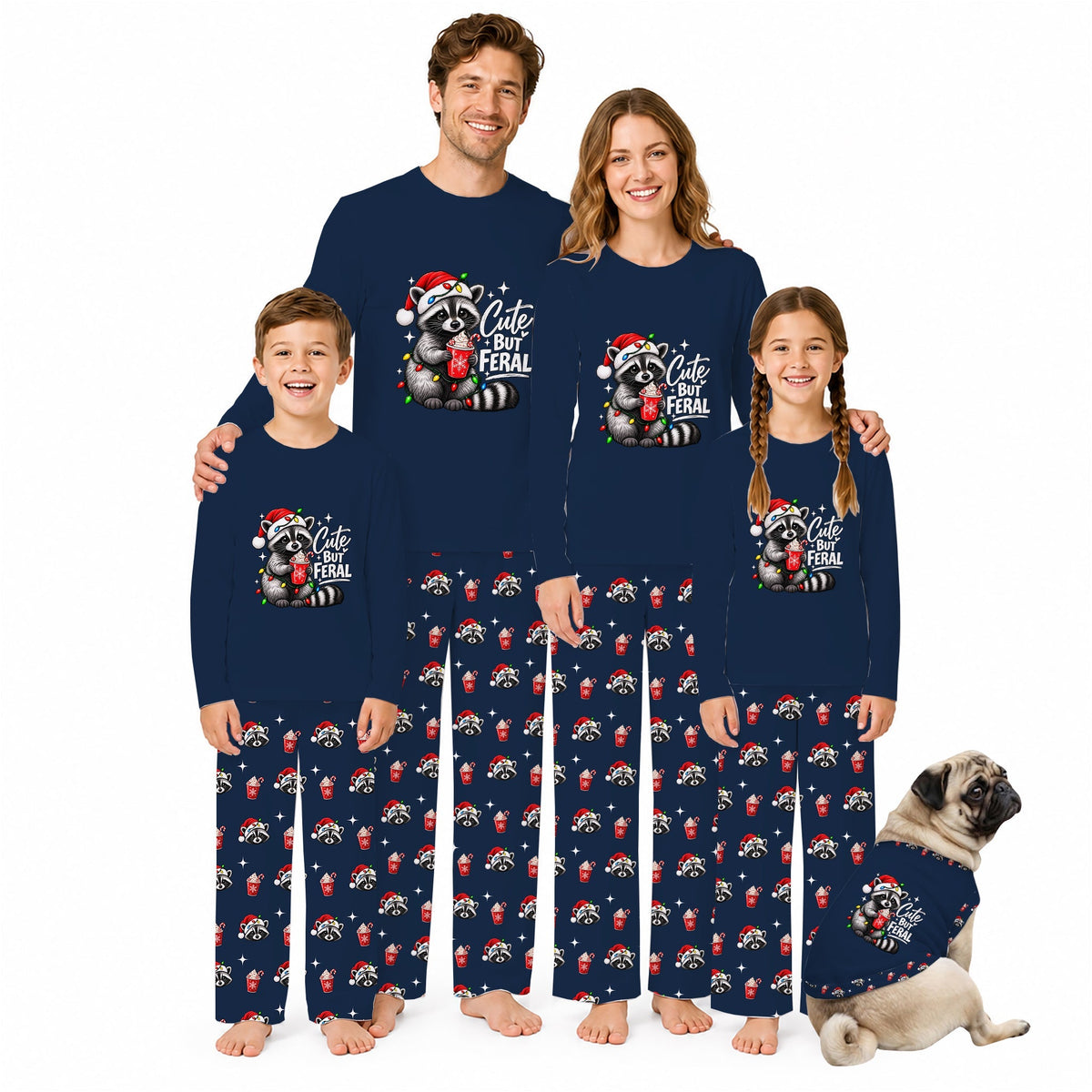 A family of four wearing matching navy blue long-sleeve pajamas with a 'Cute but Feral' raccoon graphic and red-and-white animal print pants, posed with a small matching dog on a white background.