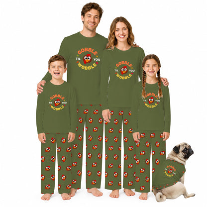 A family of four wearing matching Olive Green pajamas with a Red and yellow 'COBBLE THE YOU WROBLE' graphic, standing together on a White background, with a small pug dog wearing a matching pajama shirt at the bottom right.