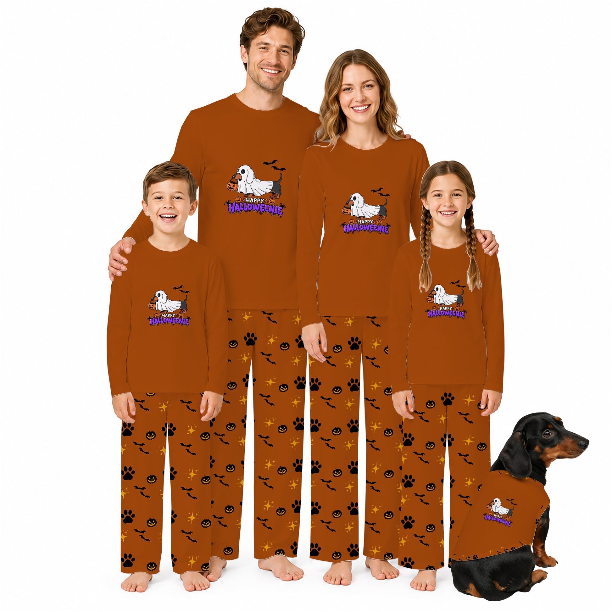 A family of four and a dog wearing matching Halloween-themed long-sleeve pajamas. The pajamas are rust brown with Black and orange pumpkin and bat patterns, and feature a White dachshund graphic with Purple 'Halloween Dog' text.