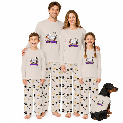 A family of four and a dog wearing matching long-sleeve pajamas with a cartoon dog graphic and 'Halloween' text on the chest, plus patterned pants with paw prints, bats, and treats, posed against a plain White background.